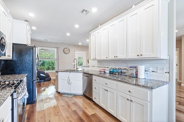 kitchen featuring visible vents, white cabinets, light wood-style flooring, appliances with stainless steel finishes, and a sink