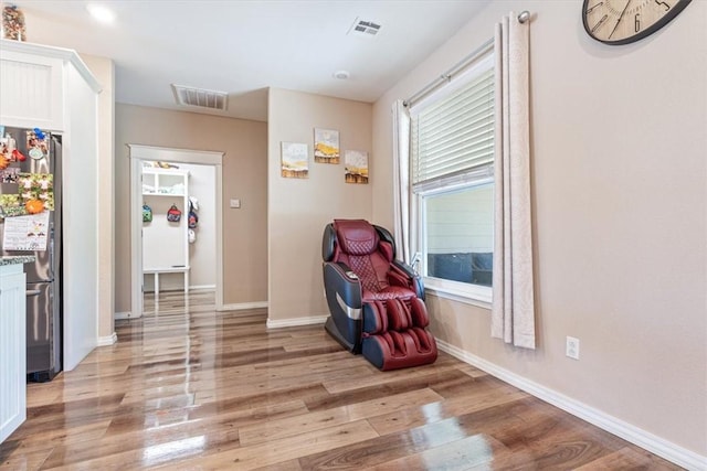 sitting room featuring visible vents, light wood-style flooring, and baseboards