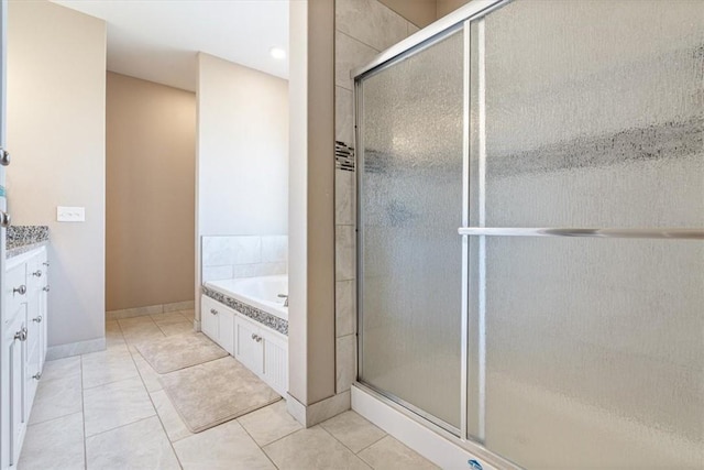 bathroom featuring a garden tub, a shower stall, vanity, tile patterned flooring, and baseboards