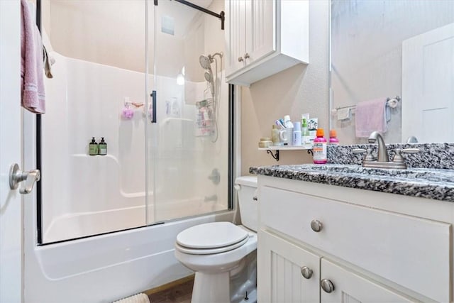 full bathroom featuring toilet, combined bath / shower with glass door, and vanity