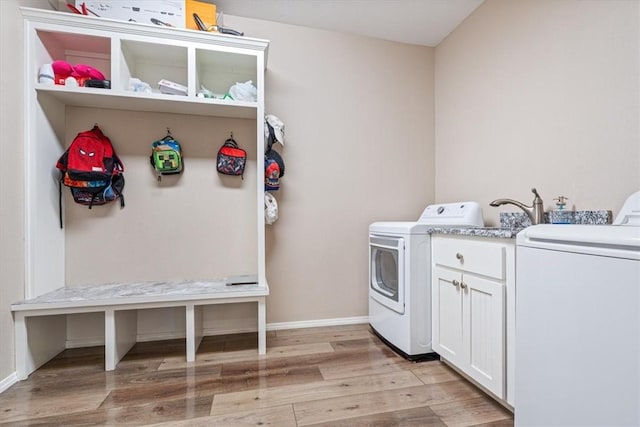 washroom featuring cabinet space, light wood-style flooring, baseboards, and separate washer and dryer