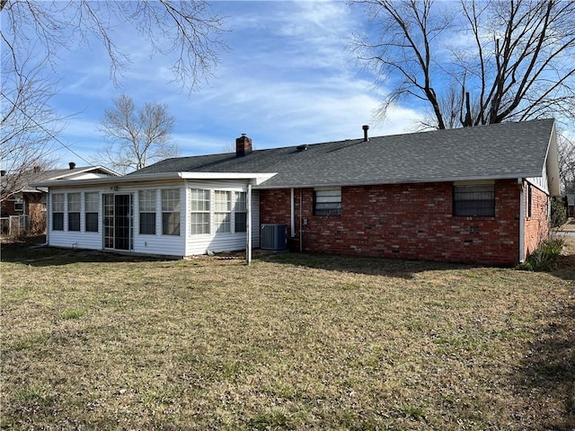 back of house with central AC unit, brick siding, a sunroom, a yard, and a chimney