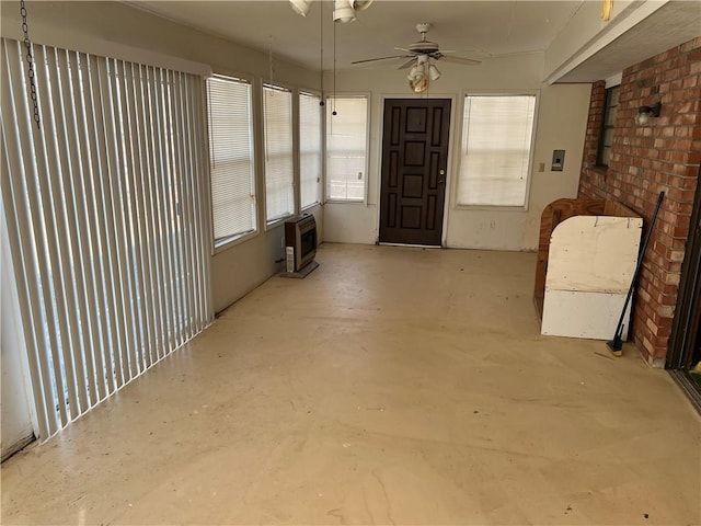 interior space with heating unit, brick wall, ceiling fan, and concrete flooring