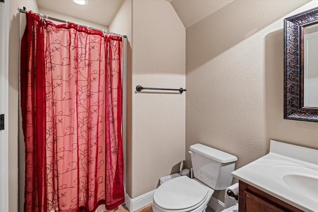 bathroom with toilet, a textured wall, curtained shower, and vanity