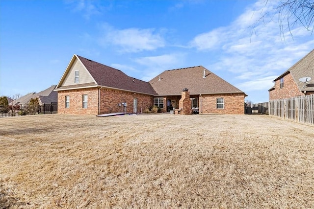 rear view of property featuring fence private yard, brick siding, and a yard