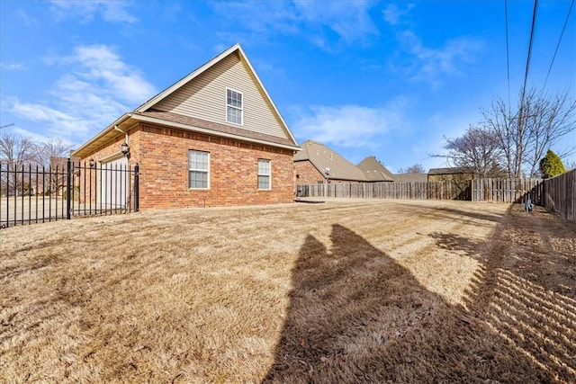 rear view of house featuring a garage, a yard, a fenced backyard, and brick siding