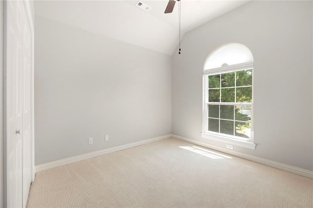 carpeted empty room with ceiling fan, visible vents, vaulted ceiling, and baseboards