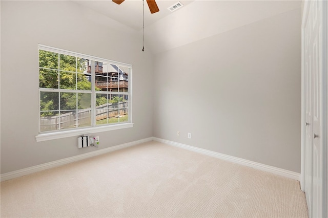 empty room featuring light carpet, baseboards, visible vents, a ceiling fan, and vaulted ceiling