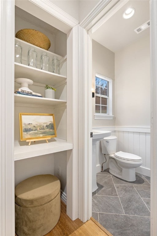 bathroom featuring wainscoting, visible vents, and toilet