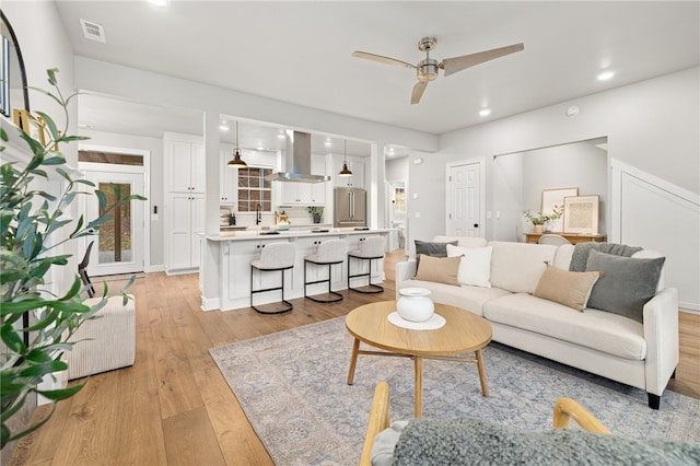 living area with a ceiling fan, light wood-type flooring, visible vents, and recessed lighting