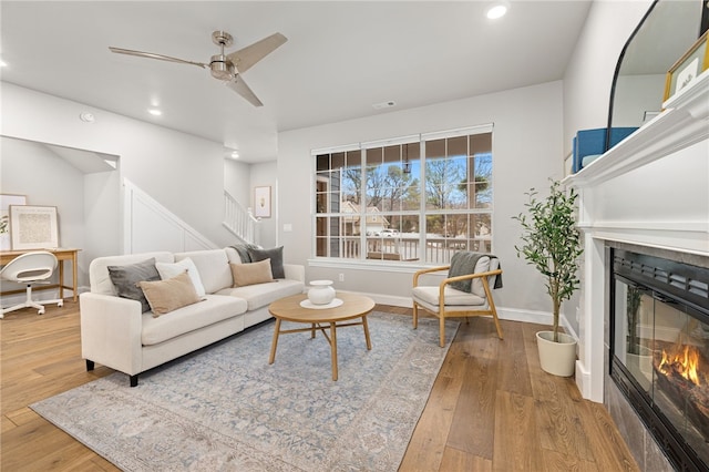 living room with visible vents, stairway, hardwood / wood-style floors, and a glass covered fireplace