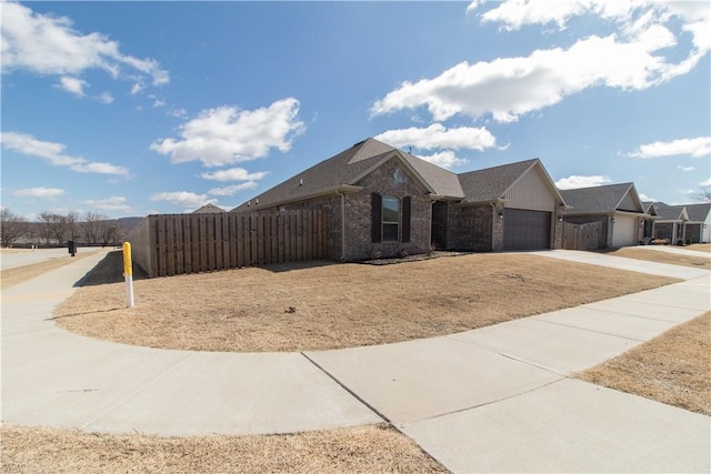 view of front of house featuring a garage, driveway, brick siding, and fence