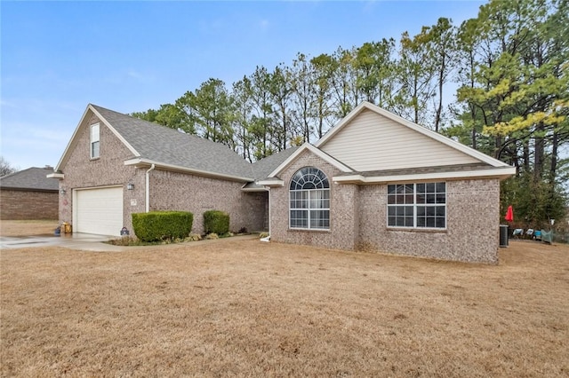 ranch-style house featuring driveway, brick siding, a shingled roof, central AC, and a front yard