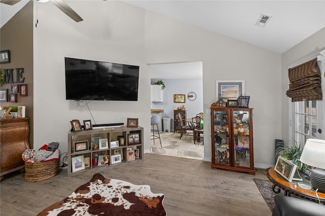 living area with ceiling fan, visible vents, vaulted ceiling, and wood finished floors