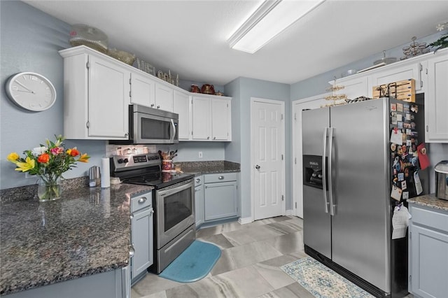 kitchen featuring dark stone counters, stainless steel appliances, and white cabinets