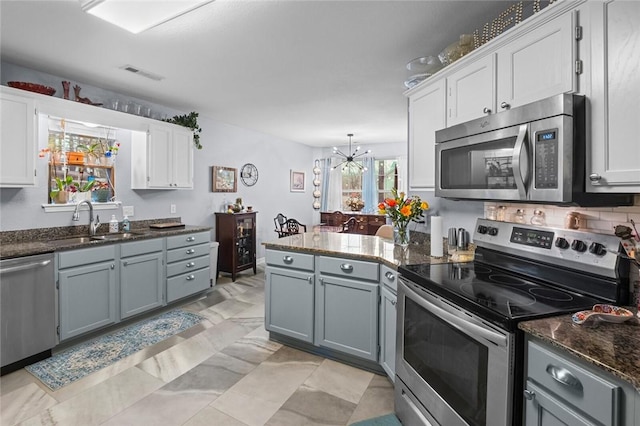 kitchen featuring stainless steel appliances, visible vents, a sink, a chandelier, and a peninsula