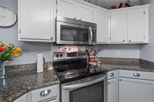 kitchen with white cabinets, stainless steel appliances, and dark stone countertops