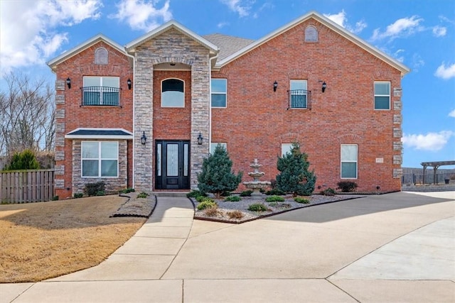 view of front of home with stone siding, brick siding, fence, and a front lawn