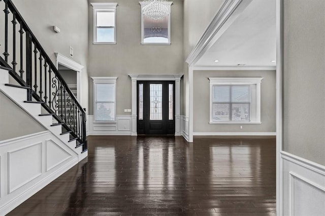 foyer with a notable chandelier, a decorative wall, stairs, and wood finished floors