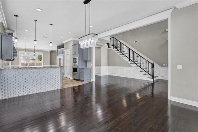 unfurnished living room with wainscoting, stairway, crown molding, and wood finished floors