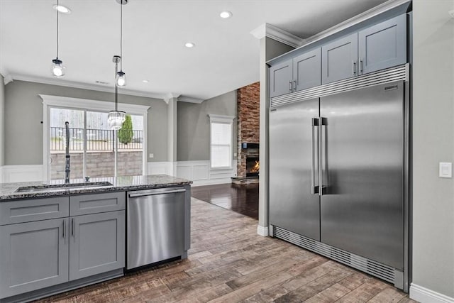 kitchen with appliances with stainless steel finishes, gray cabinets, crown molding, and a sink