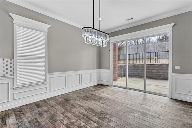 unfurnished dining area featuring a notable chandelier, wood finished floors, visible vents, and crown molding