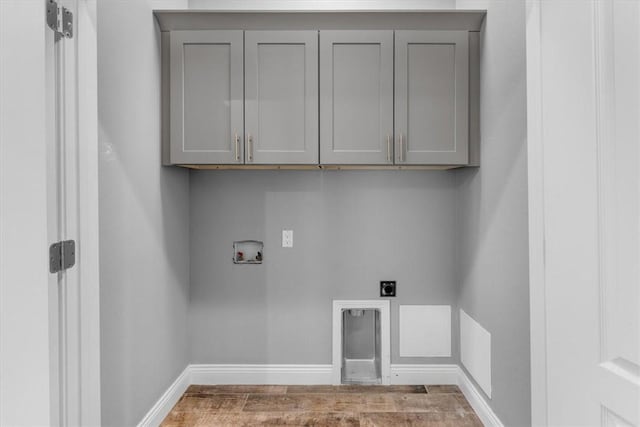 laundry room featuring hookup for an electric dryer, washer hookup, wood finished floors, baseboards, and cabinet space