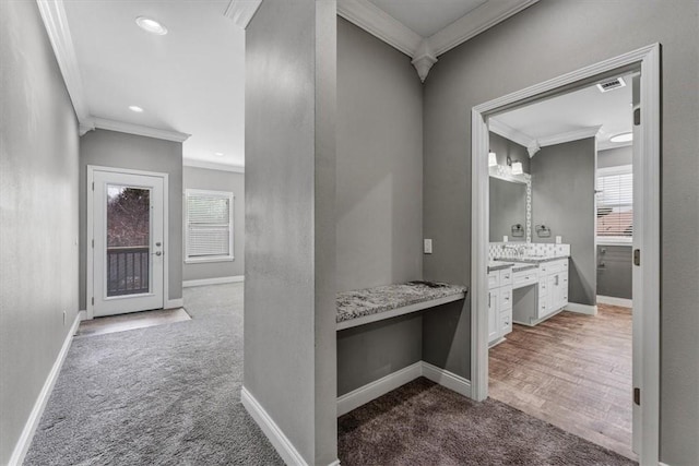 hall featuring carpet flooring, crown molding, and baseboards