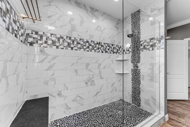 full bathroom featuring ornamental molding, a tile shower, and wood finished floors