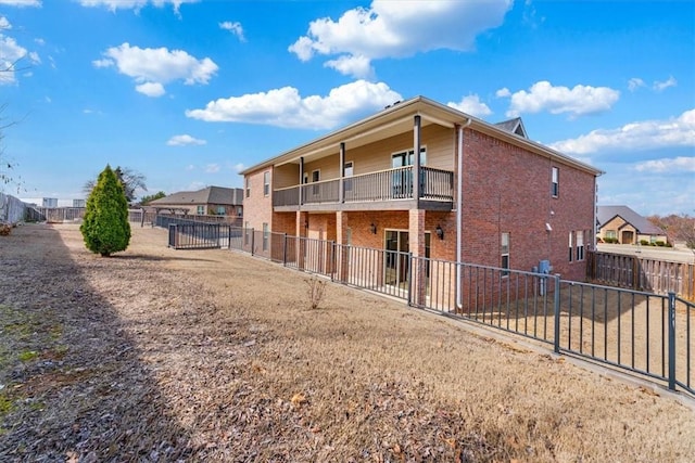 rear view of house featuring brick siding, a patio, a balcony, and a fenced backyard