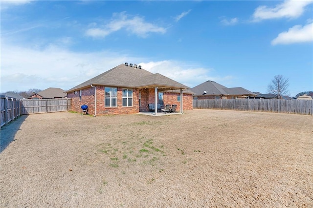 back of house featuring a patio area, a fenced backyard, a lawn, and brick siding