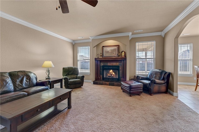 carpeted living area featuring ornamental molding, plenty of natural light, a tile fireplace, and visible vents