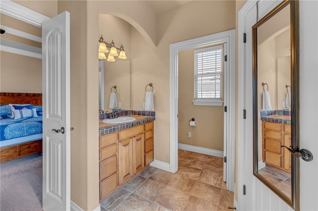 ensuite bathroom with ensuite bath, baseboards, and vanity