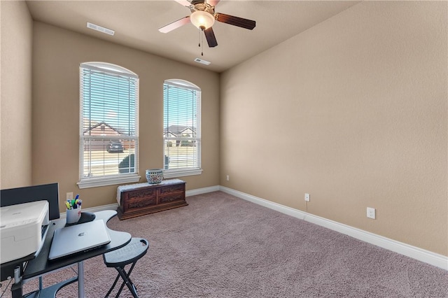 carpeted office space featuring baseboards, visible vents, and a ceiling fan