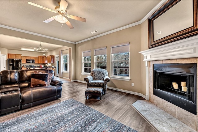 living room featuring a tile fireplace, crown molding, and wood finished floors