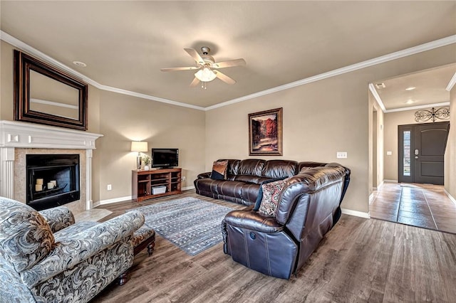 living area with baseboards, a fireplace, wood finished floors, and crown molding