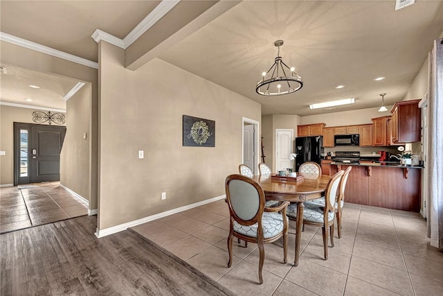 dining space with light tile patterned floors, baseboards, ornamental molding, and a notable chandelier