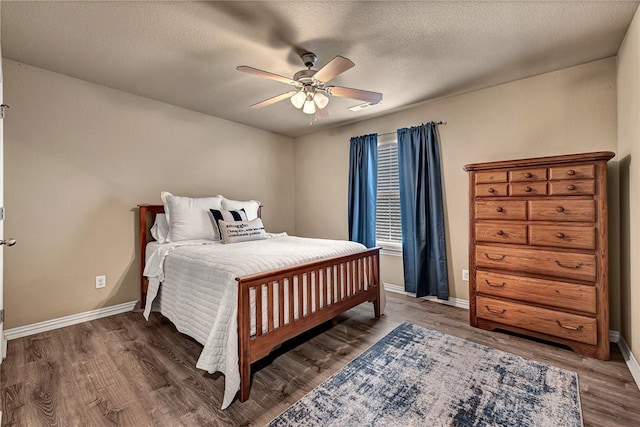 bedroom with baseboards, a textured ceiling, wood finished floors, and visible vents