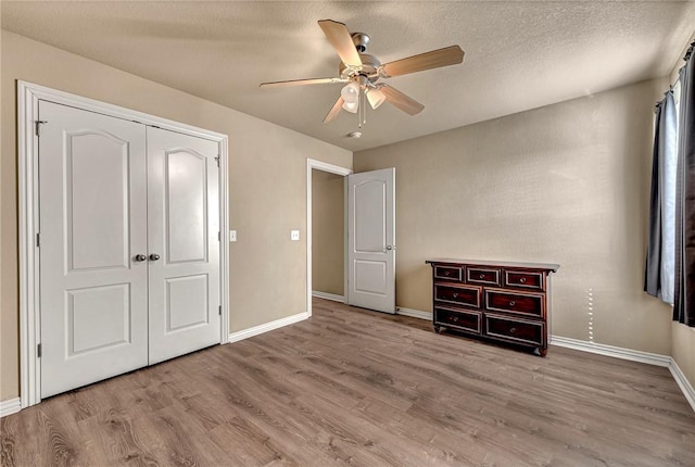 unfurnished bedroom with a ceiling fan, baseboards, wood finished floors, and a closet