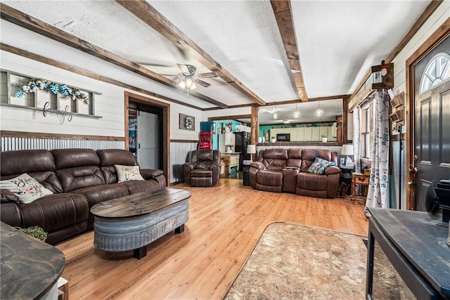 living room featuring beam ceiling, a textured ceiling, ceiling fan, and wood finished floors