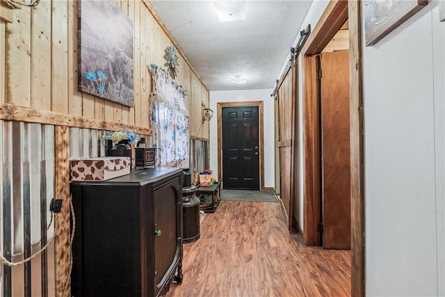 hallway featuring a barn door, wooden walls, and wood finished floors