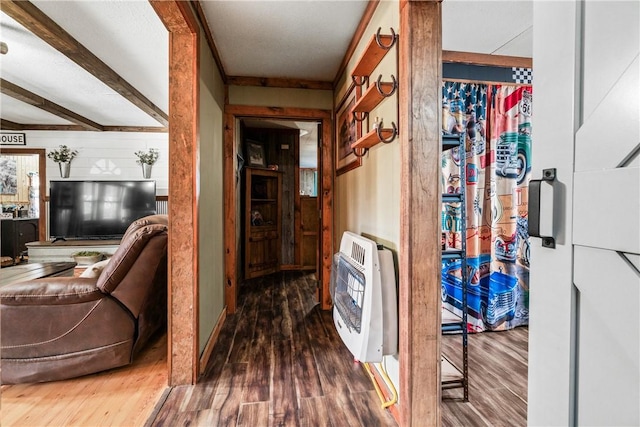 corridor with heating unit, beam ceiling, wood walls, and wood finished floors