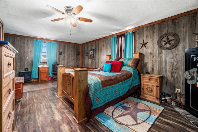 bedroom featuring wooden walls, wood finished floors, a wood stove, and a textured ceiling