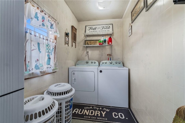 washroom featuring laundry area, tile walls, independent washer and dryer, and a textured ceiling