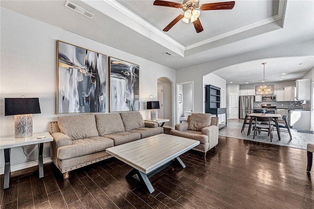 living room featuring visible vents, arched walkways, a raised ceiling, and wood finished floors