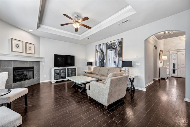 living room with arched walkways, wood finished floors, a raised ceiling, and visible vents