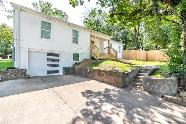 view of front of property featuring a garage, driveway, and fence