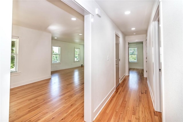 hall with light wood-style floors, recessed lighting, and baseboards