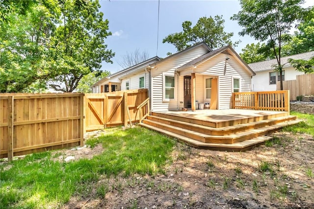 rear view of property with a gate, fence, and a wooden deck