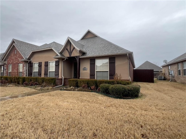 view of front of home featuring brick siding, roof with shingles, a front lawn, and stucco siding